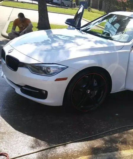 White BMW sedan with black wheels during a hand wash